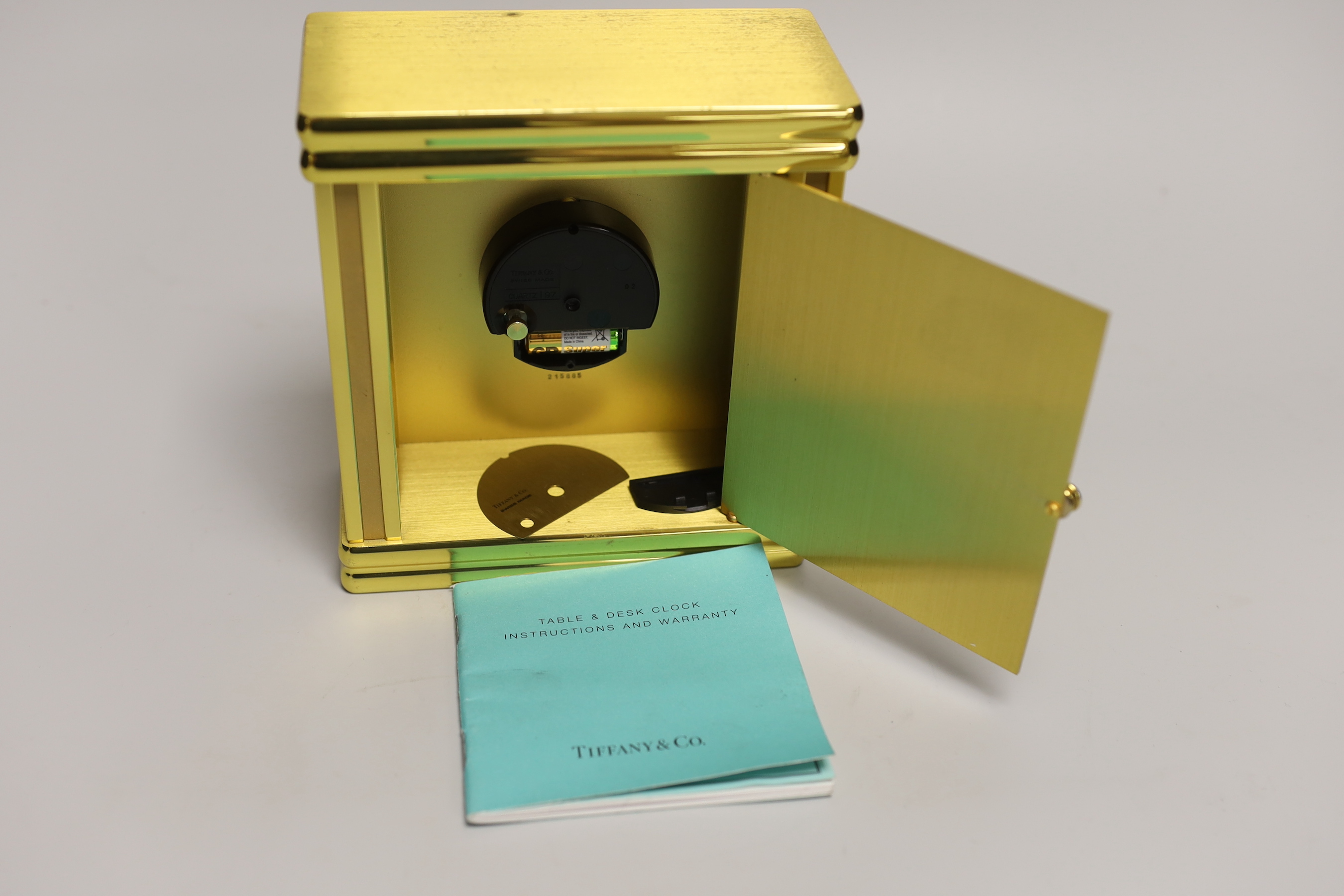 A Tiffany & Co. Swiss made brass clock with booklet, numbered 215885, 16cm high